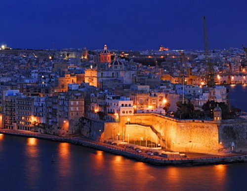The floodlit Fort St. Angelo on the tip of the peninsula Vittoriosa, Birgu, as seen from Valletta across the Grand Harbor at the blue hour after sunset, Malta, Europe